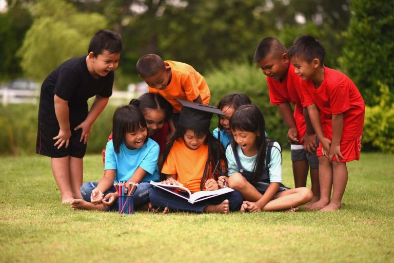 Group-of-children-lying-reading-on-grass-field