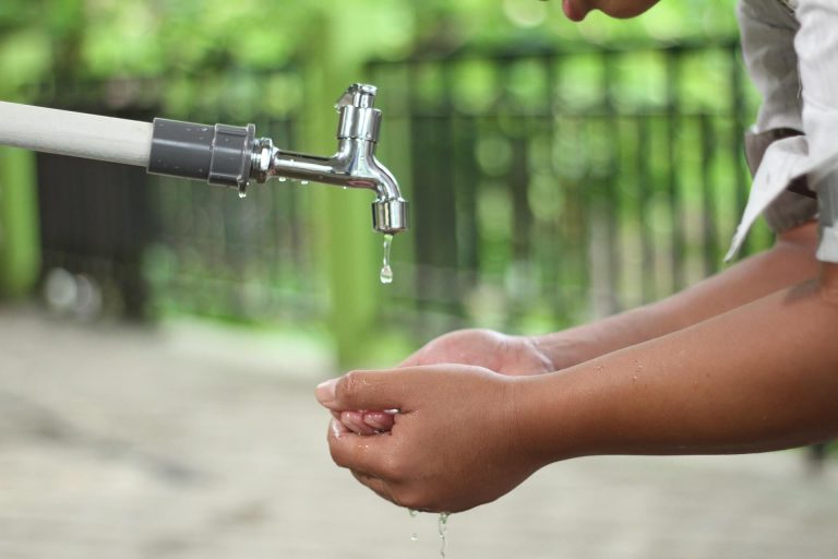 person-washing-hands-in-open-faucet